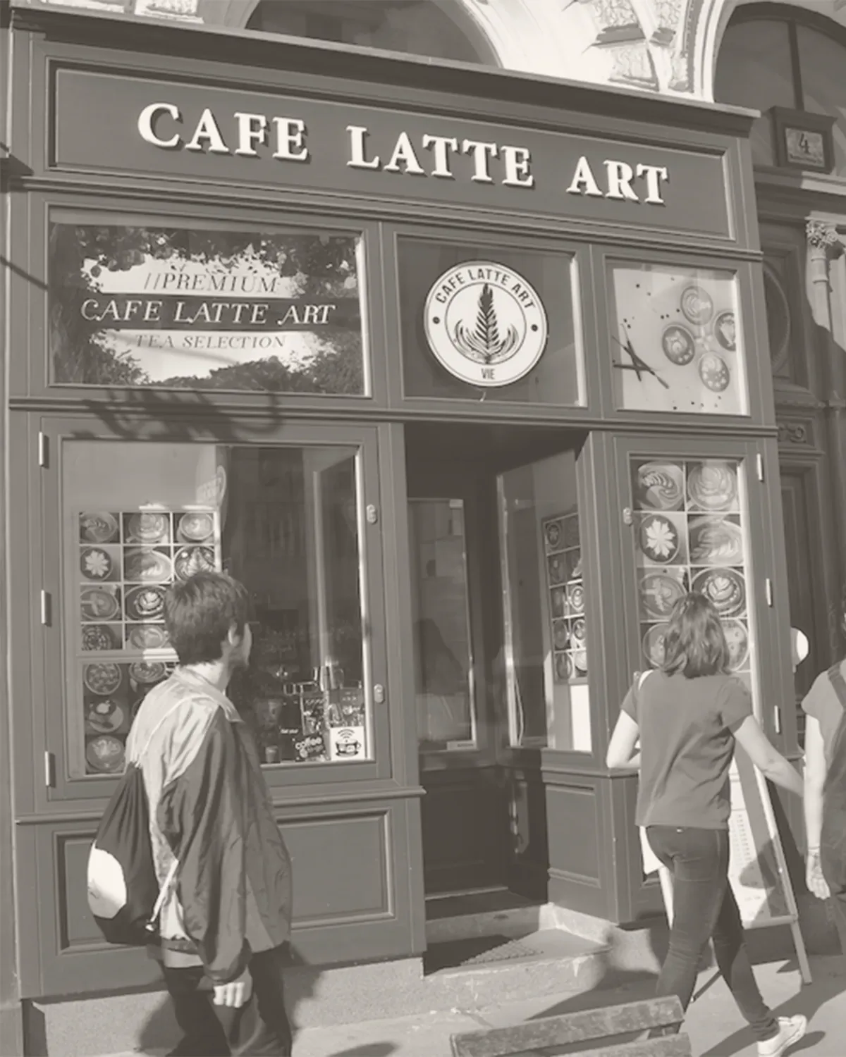 Die Außenansicht von Cafe Latte Art in der Universitätsstraße 4 in Wien, Schwarzweißaufnahme mit Passanten vor der Auslage